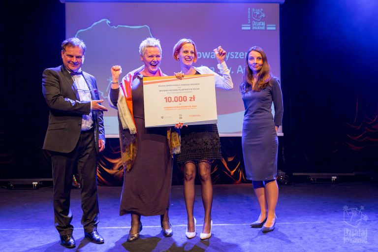 Przedstawicielki Stowarzyszenia Kraina św. Anny odbierają symboliczny czek z nagrodą w konkursie na dobre praktyki