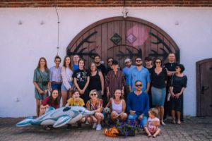 Zdjęcie przedstawia grupę młodych ludzi wraz z&nbsp;nauczycielami, na&nbsp;tle dużych, drewnianych drzwi.