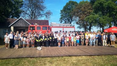 Zdjęcie przedstawia bardzo dużą grupę ludzi, ustawionych na tle wozu strażackiego