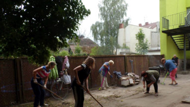 Wolontariusze grabią trawę w ogrodzie