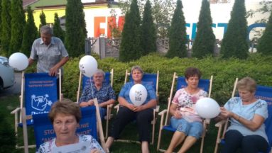 Uczestnicy spotkania: Kino w plenerze na niebieskich leżakach z logo Działaj Lokalnie.