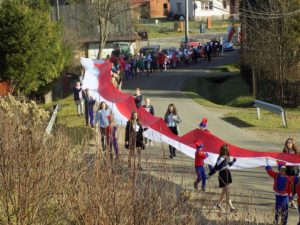 Młodzież i&nbsp;dzieci z&nbsp;Ropienki maszerują ze 100-tu metrową flagą państwową