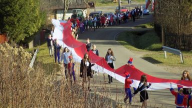 Młodzież i dzieci z Ropienki maszerują ze 100-tu metrową flagą państwową