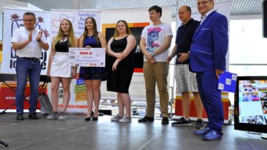 Zdjęcie przedstawia grupę odświętnie ubranych osób. Jedna z nich trzyma symboliczny czek na grant programu Działaj Lokalnie.