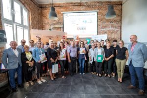 Zdjęcie przedstawia grupę os&oacute;b pozujących do&nbsp;zdjęcia, trzymających dyplomy dla&nbsp;grantobiorc&oacute;w.