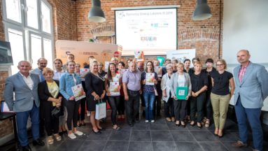 Zdjęcie przedstawia grupę osób pozujących do zdjęcia, trzymających dyplomy dla grantobiorców.