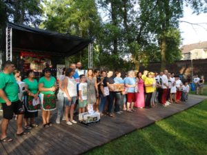Drużyny biorące udział w konkursie Zdjęcie przedstawia grupę ludzi stojącą na plenerowej scenie, pozujących do zdjęcia.
