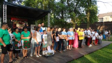 Zdjęcie przedstawia grupę ludzi stojącą na plenerowej scenie, pozujących do zdjęcia.