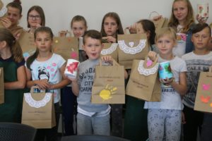 Zdjęcie przedstawia grupę dzieci pozujących do&nbsp;zdjęcia z&nbsp;własnoręcznie wykonanymi papierowymi torbami.