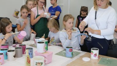 Zdjęcie przedstawia grupę dzieci i dorosłych podczas warsztatów decoupage.
