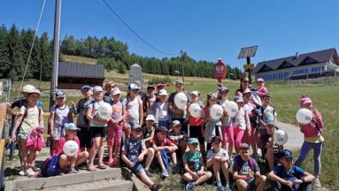 Zdjęcie przedstawia grupę dzieci w plenerze, pozujących do zdjęcia.