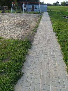 Zdjęcie przedstawia chodnik wyłożony nową kostką brukową.