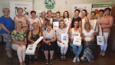 Zdjęcie przedstawia grupę osób trzymających dyplomy i pozujących do zdjęcia.