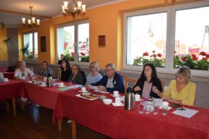 Warsztaty dziennikarskie w ramach projektu "Wieści gminne - co w trawie piszczy" Zdjęcie przedstawia osoby siedzące przy stole, biorące udział w warsztatach dziennikarskich.