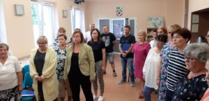 Zdjęcie przedstawia grupę os&oacute;b podczas pr&oacute;by ch&oacute;ru.