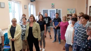 Zdjęcie przedstawia grupę osób podczas próby chóru.