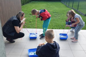 Zdjęcie przedstawia tr&oacute;jkę dzieci i&nbsp;instruktorkę podczas ćwiczeń.