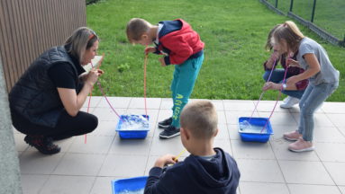 Zdjęcie przedstawia trójkę dzieci i instruktorkę podczas ćwiczeń.