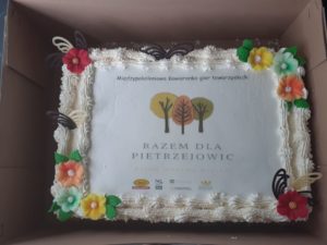 Tort ze zdjęciem logotypu Stowarzyszenia Razem dla&nbsp;Pietrzejowic oraz&nbsp;Działaj Lokalnie z&nbsp;napisem Międzypokoleniowa Kawiarenka gier towarzyskich