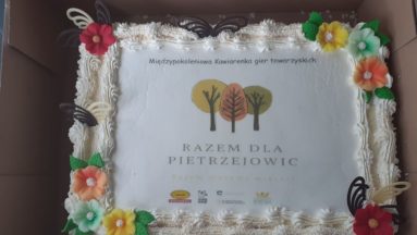 Tort ze zdjęciem logotypu Stowarzyszenia Razem dla Pietrzejowic oraz Działaj Lokalnie z napisem Międzypokoleniowa Kawiarenka gier towarzyskich