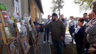 Na zdjęciu widać plenerową wystawę prac plastycznych i widzów.