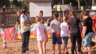 Zdjęcie przedstawia osoby stojące w grupie na plaży podczas jednej z zabaw.