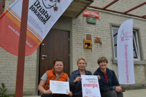 Miejsce spotkań mieszkańców Kożuchowa Zdjęcie przedstawia osoby pozujące do zdjęcia przed budynkiem, pokazujące podpisane umowy.