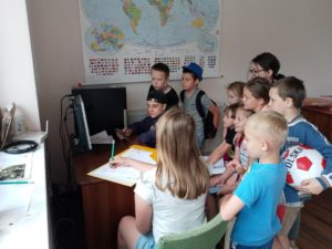 Zdjęcie przedstawia grupę dzieci przed komputerem.