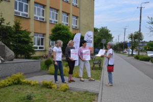 Na zdjęciu widać grupę os&oacute;b stojącą przed budynkiem.