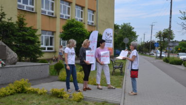Na zdjęciu widać grupę osób stojącą przed budynkiem.
