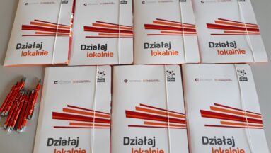 Na zdjęciu widać ułożone na stole teczki z umowami.