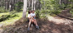 Marsz nordic walking pod hasłem"Idąc ku lepszemu" Dwie uczestniczki siedzą na poboczu, odpoczywając