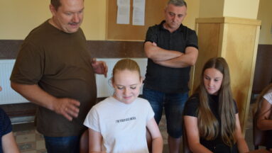 Na zdjęciu pan Ireneusz wraz z grupą młodzieży przeglądają wykonane przez nich zdjęcia