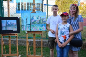 Rodzina stoi obok&nbsp;swoich prac plastycznych