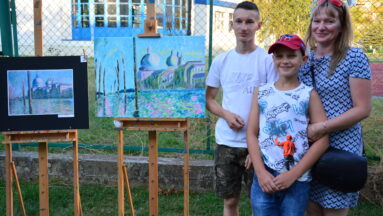 Rodzina stoi obok swoich prac plastycznych