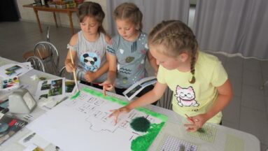 Dzieci malujące na kartce podczas warsztatów