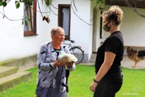 Osoba daje chleb seniorce