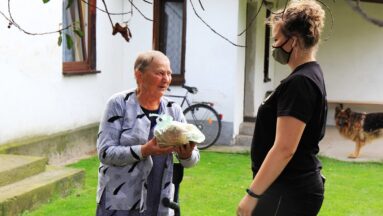 Osoba daje chleb seniorce