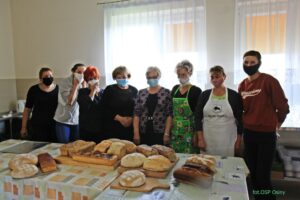 Osoby pozują do&nbsp;zdjęcia przy&nbsp;stole zastawionym chlebami