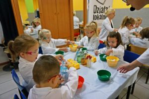Grupa dzieci siedzi przy&nbsp;stoliku w&nbsp;jadalni zamienionej w&nbsp;tymczasowe laboratorium