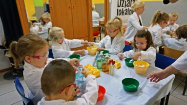 Grupa dzieci siedzi przy stoliku w jadalni zamienionej w tymczasowe laboratorium