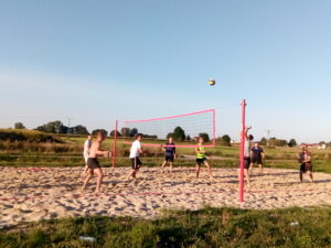 Na zdjęciu widzimy grupę os&oacute;b grających w&nbsp;siatk&oacute;wkę plażową