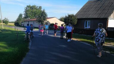 Grupa osób z kijkami w plenerze