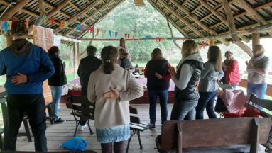 Grupa osób stoi pod wiatą i słucha prelegentki