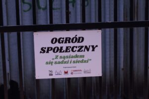 Tabliczka z&nbsp;napisem "Ogr&oacute;d społeczny" zawieszona na&nbsp;płocie