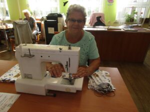 Wakacje z koronawirusem Kobieta siedzi przy maszynie do szycia