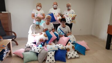 Grupa seniorów pozuje do zdjęcia pokazując uszyte fanty