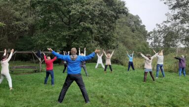 Grupa osób ćwiczy qigong w plenerze