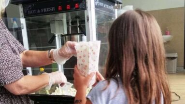Dziewczynka odbiera popcorn od wolontariuszki