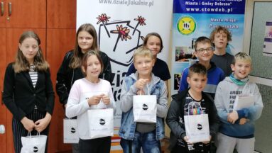 Grupa dzieci i młodzieży pozuje do zdjęcia pod banerem "Działaj Lokalnie"